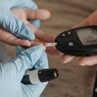 Close-up of hands checking glucose with a glucometer