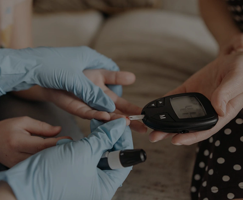Patient measuring blood glucose while others observe in a medical consultation room