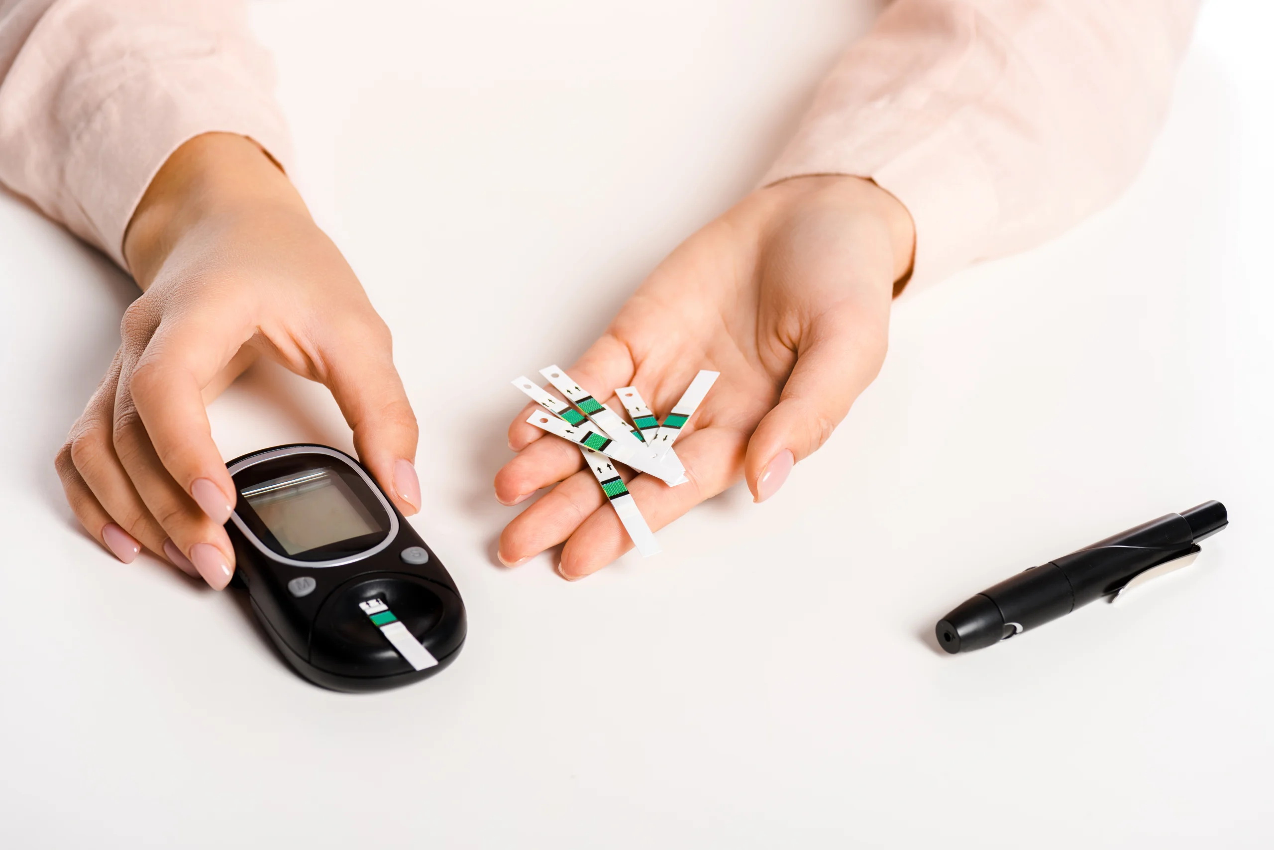 Hand holding blood sugar meter and test strip, preparing to measure glucose level.