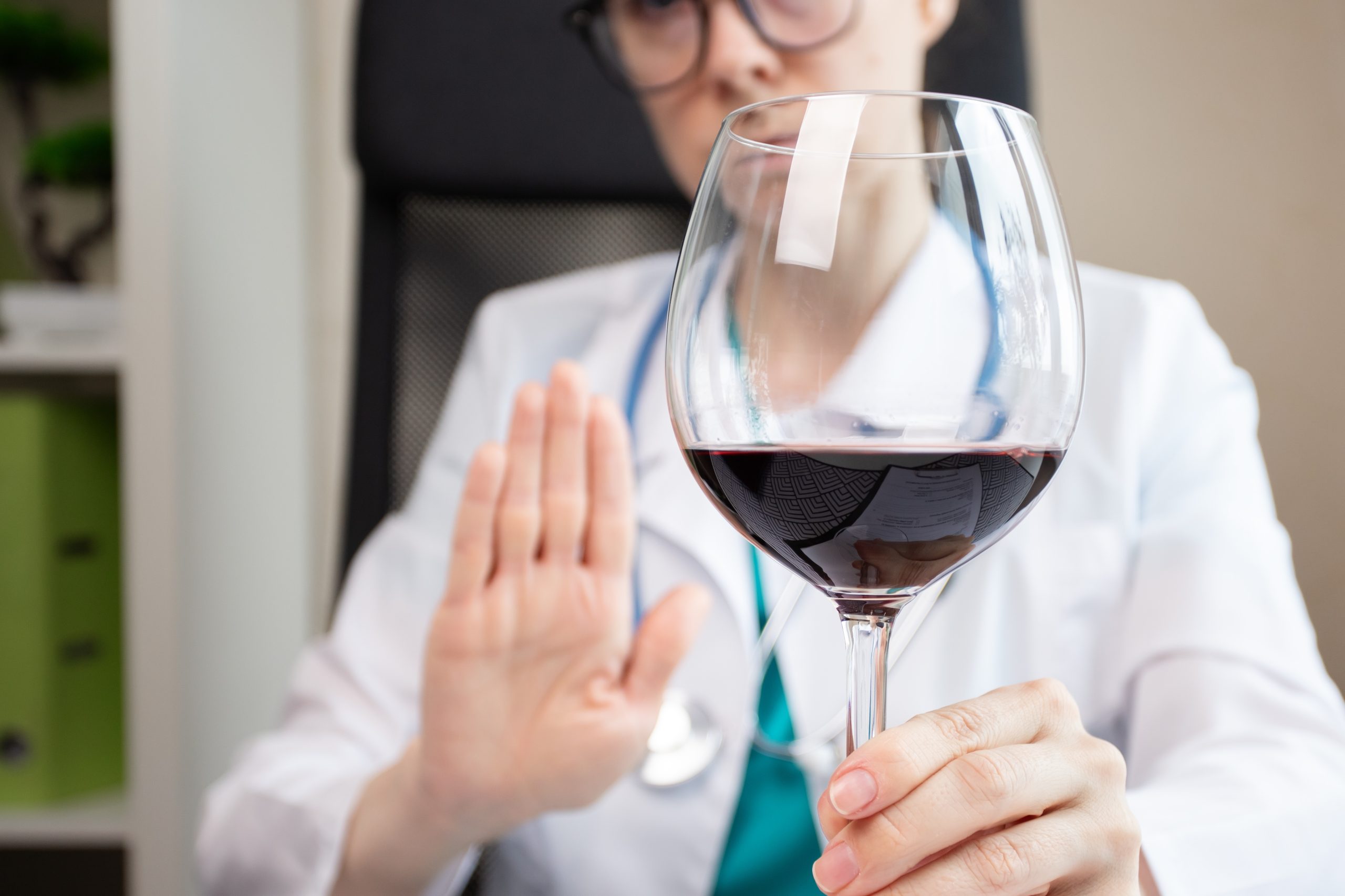 Doctor showing a stop gesture to reject alcoholic drinks, illustrating whether you can drink alcohol while taking semaglutide.