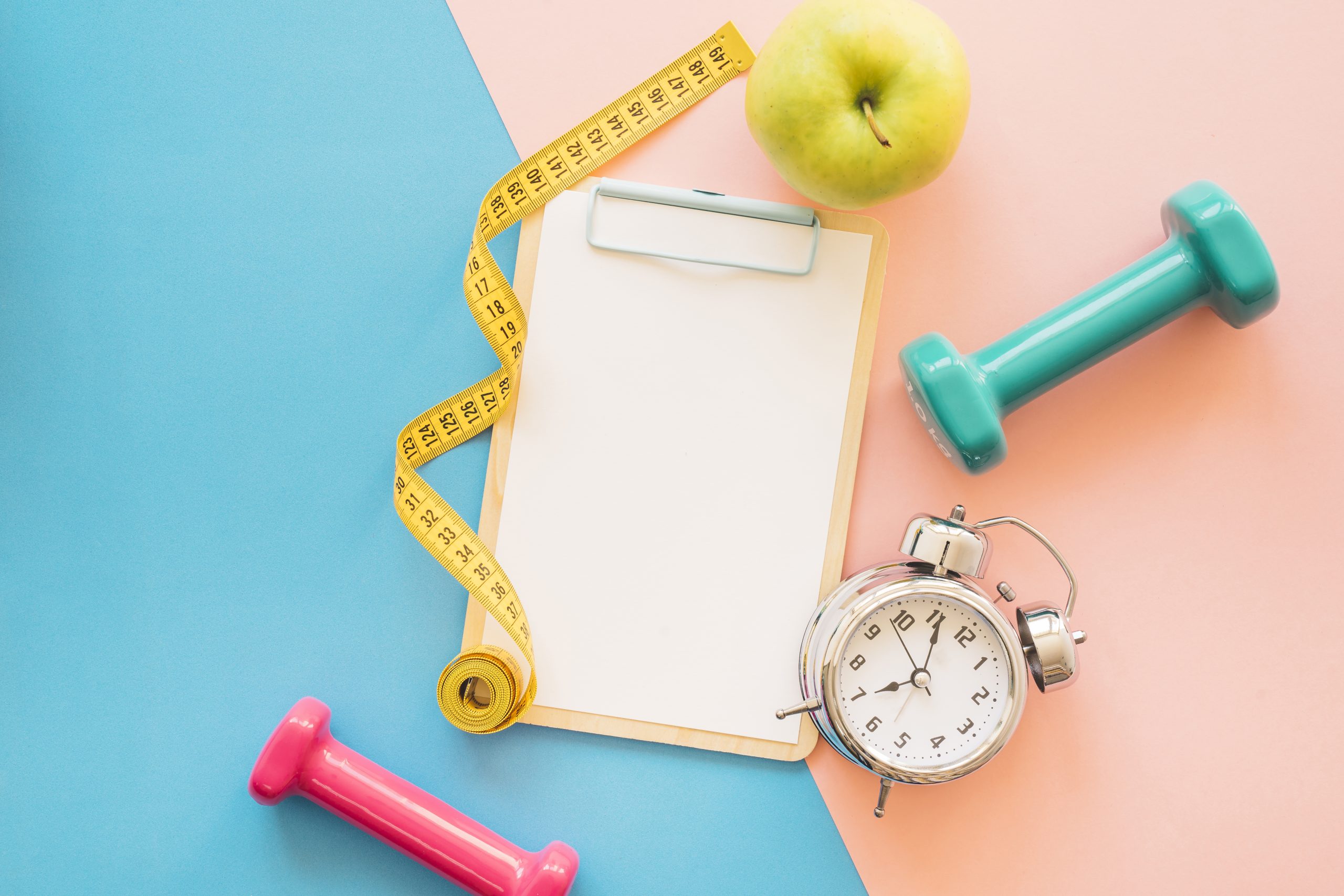 A board with paper, dumbbell, alarm clock, measuring tape, and a green apple, illustrating when semaglutide starts working for weight loss.