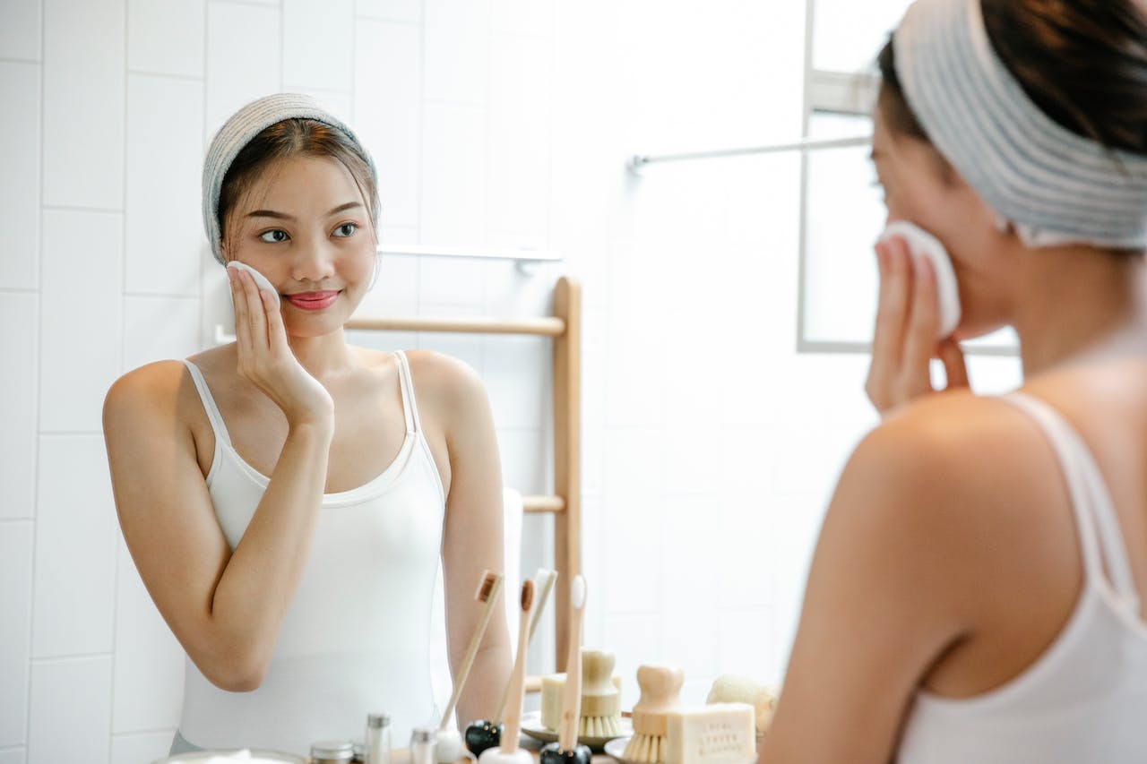 Woman with glowing skin looking in mirror showcasing peptide skincare and anti-aging benefits.