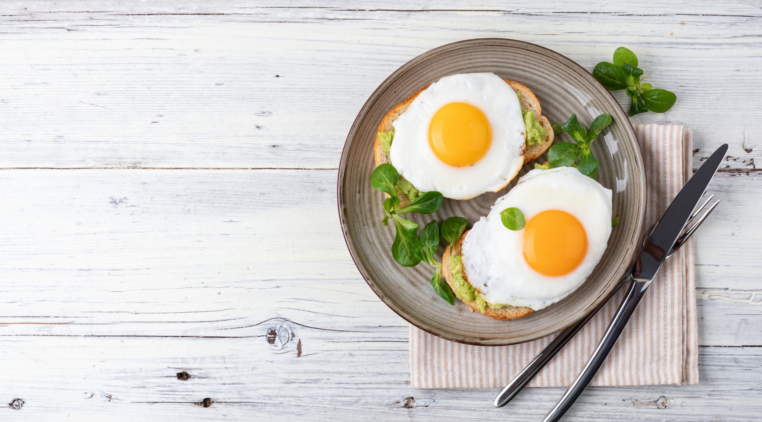 A bowl of poached eggs and greens with spoon and fork, illustrating the best keto breakfast ideas for Type 2 diabetics.