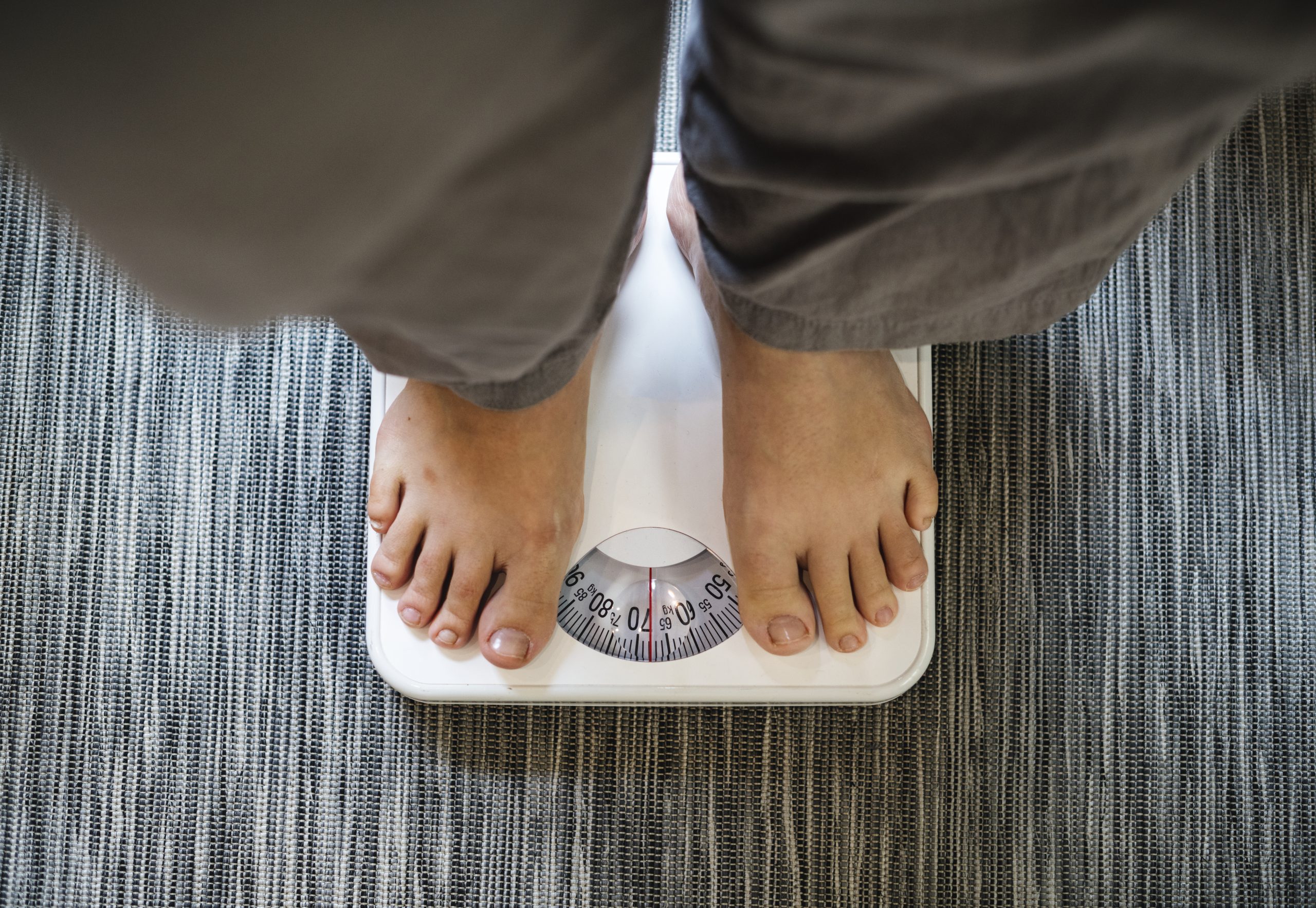 A person standing on a weighing scale, illustrating whether insulin resistance causes weight gain and how to manage it.
