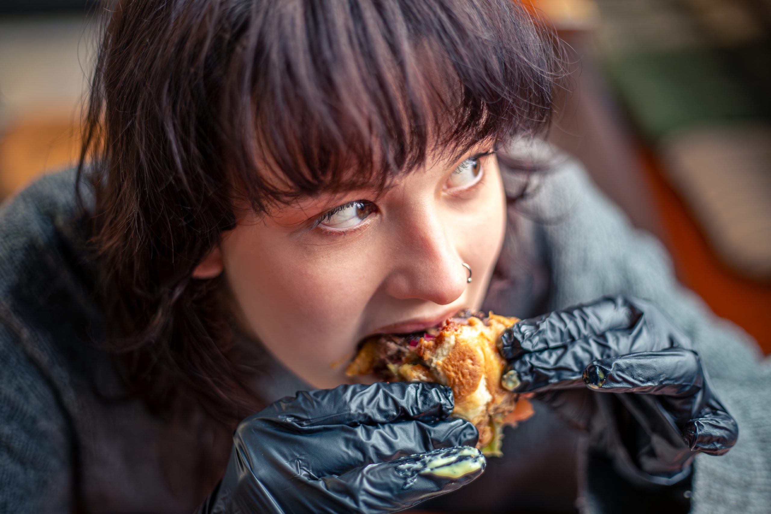 Young woman eating a burger in a restaurant, illustrating strategies to stop diabetes hunger and control appetite.